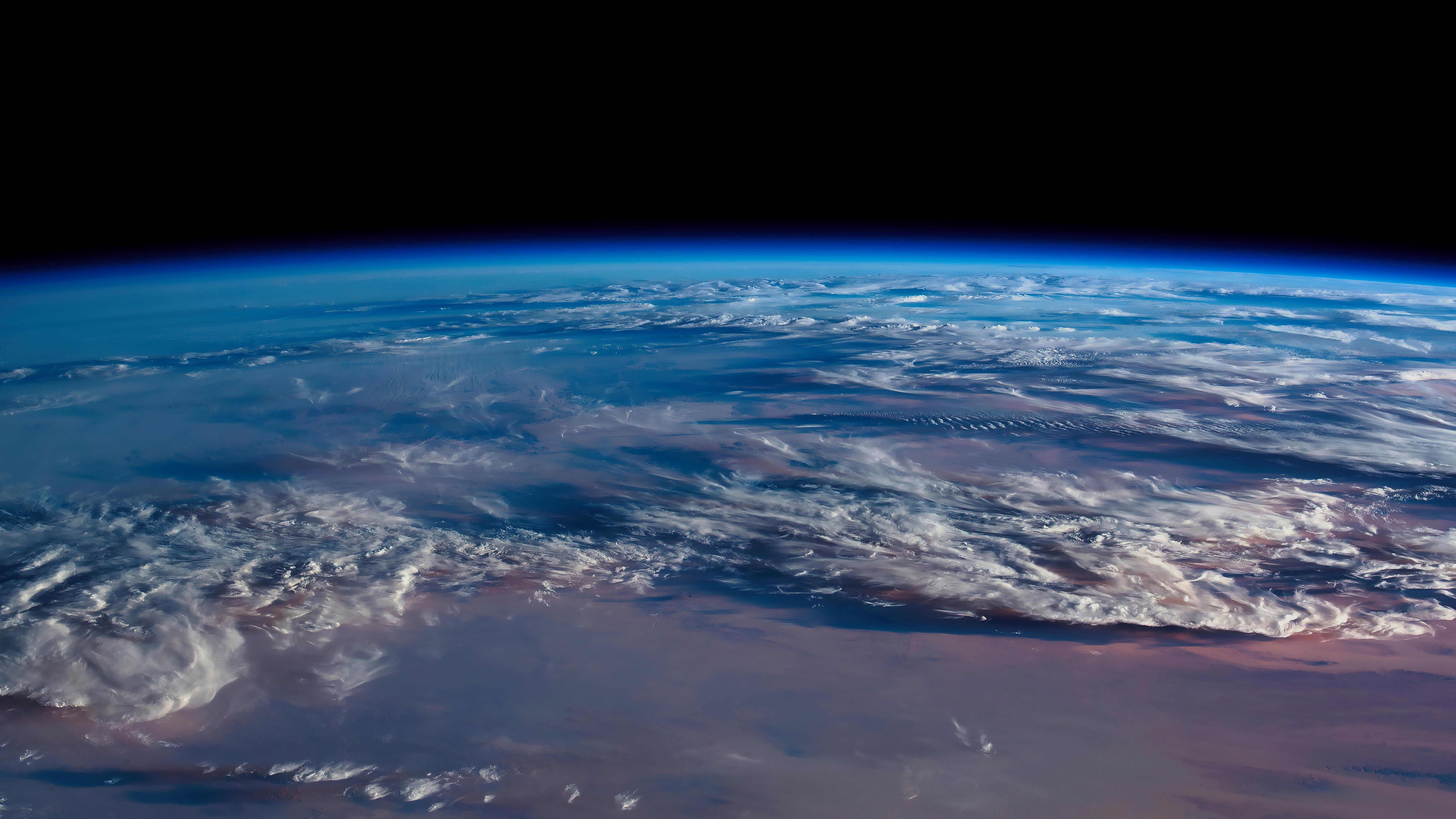 从太空中看到的广阔的地球, 大部分被云覆盖, 在外太空的黑暗中. 